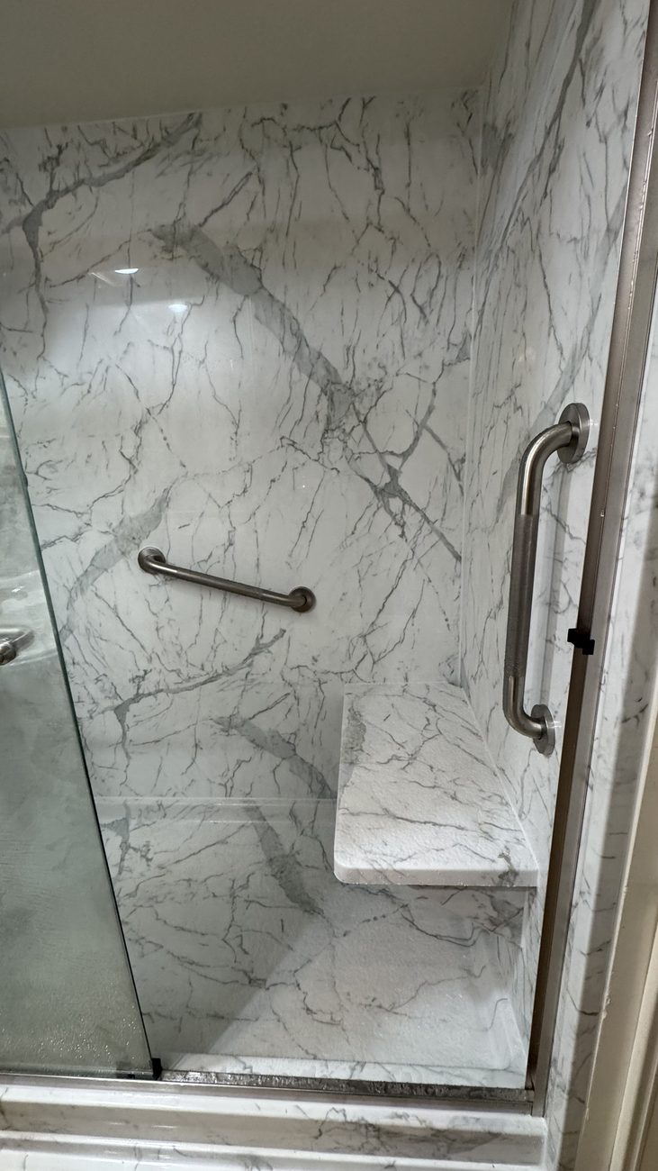 Marble-look walk-in shower with glass doors and bench