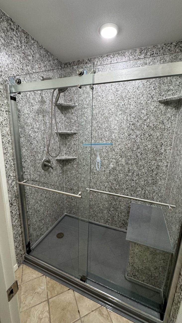 Speckled stone-look shower with glass enclosure